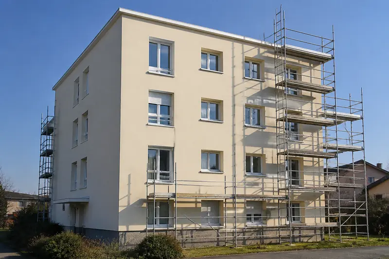 Immeuble en béton recouvert d'un enduit neuf pendant un ravalement avec échafaudage